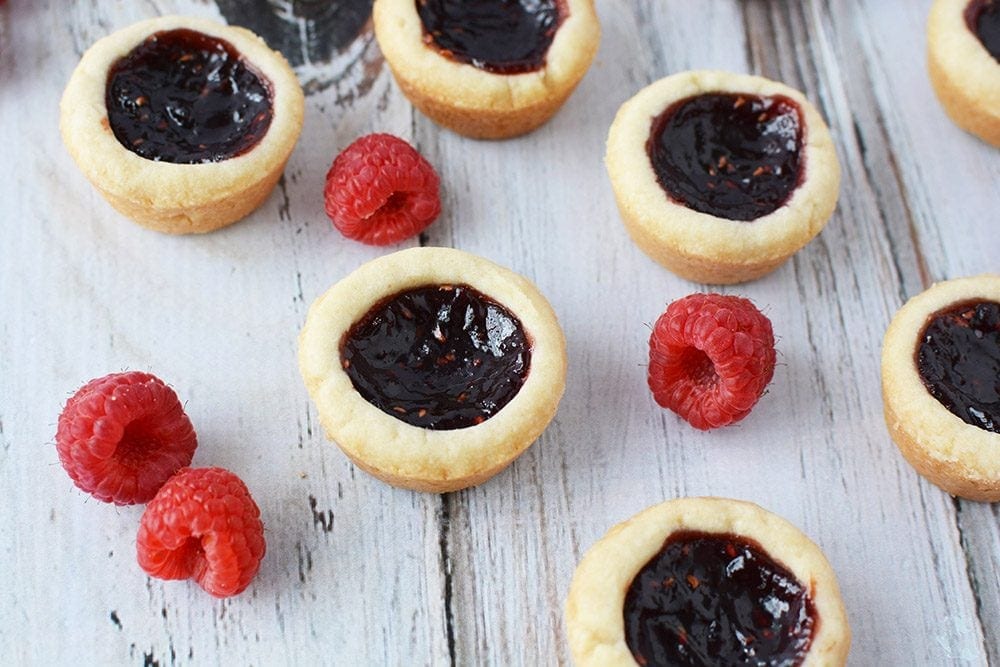 Raspberry tarts on a table with raspberries. 