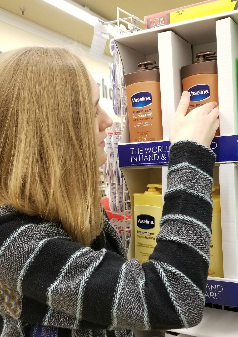 Girl taking Vaseline lotion off the shelf at a store. 
