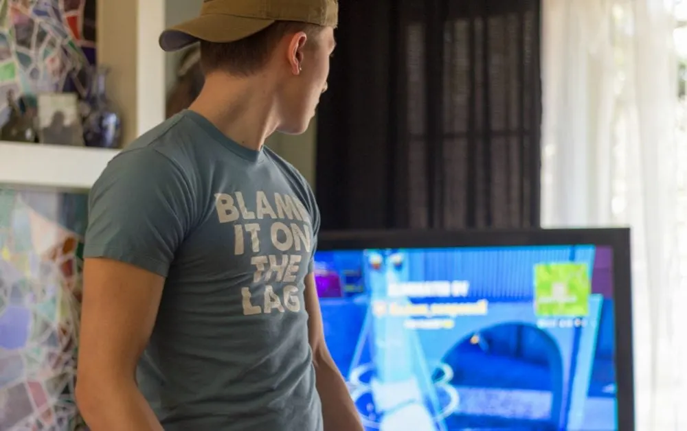 Teen in a "Blame it on the lag shirt" playing Fortnite. 