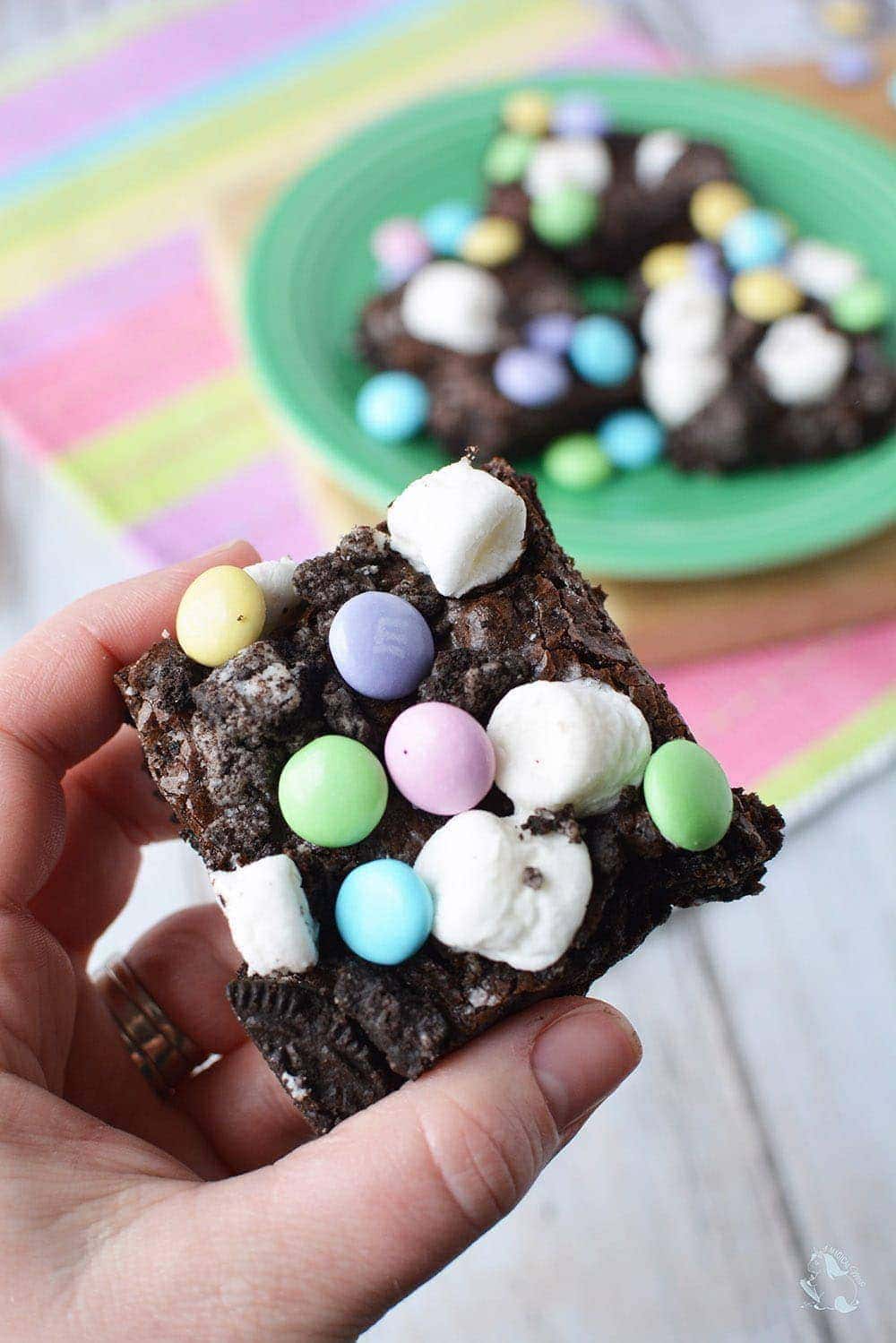 Holding a brownie with marshmallows and pastel M&Ms. 