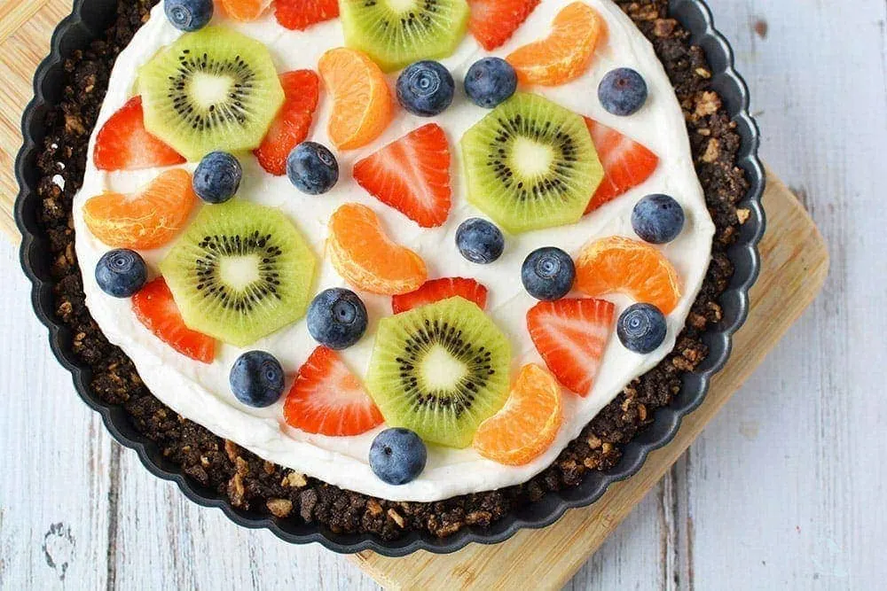 Overhead image of a fruit pizza on a board. 