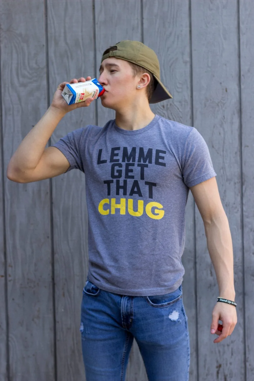 Teen drinking a protein drink in a "lemme get that chug" shirt. 