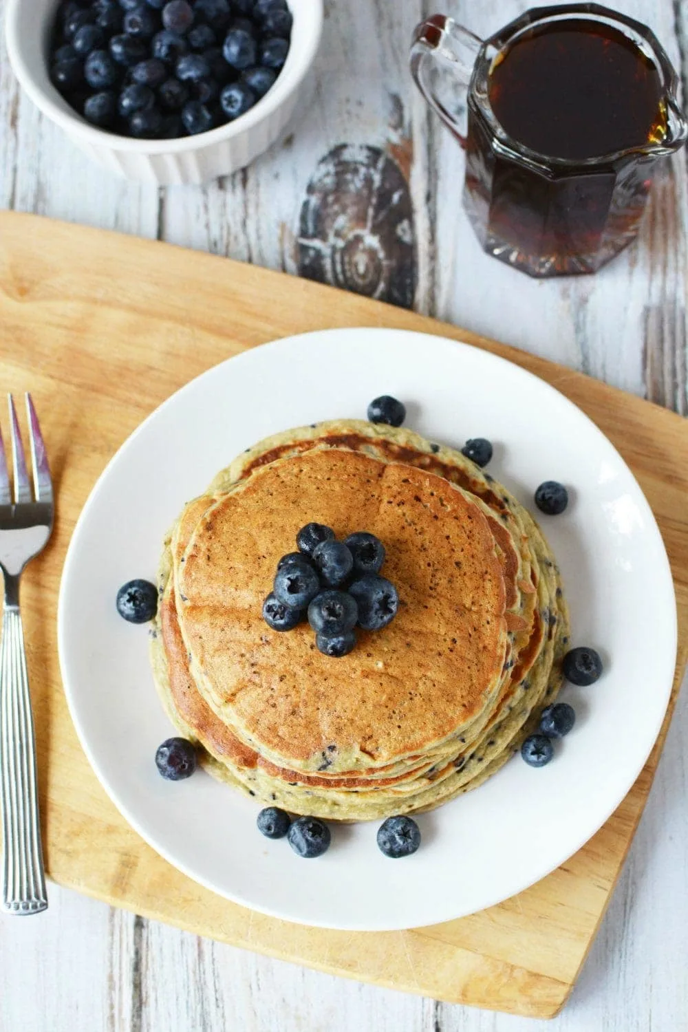 Pancakes on a plate topped with blueberries. 