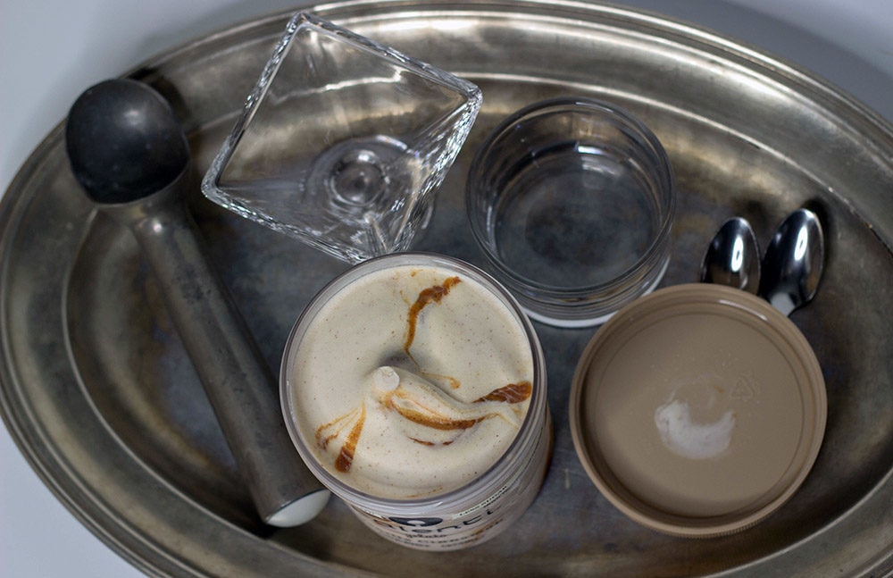 Talenti Gelato on a tray next to an ice cream scooper, dish, and spoons.