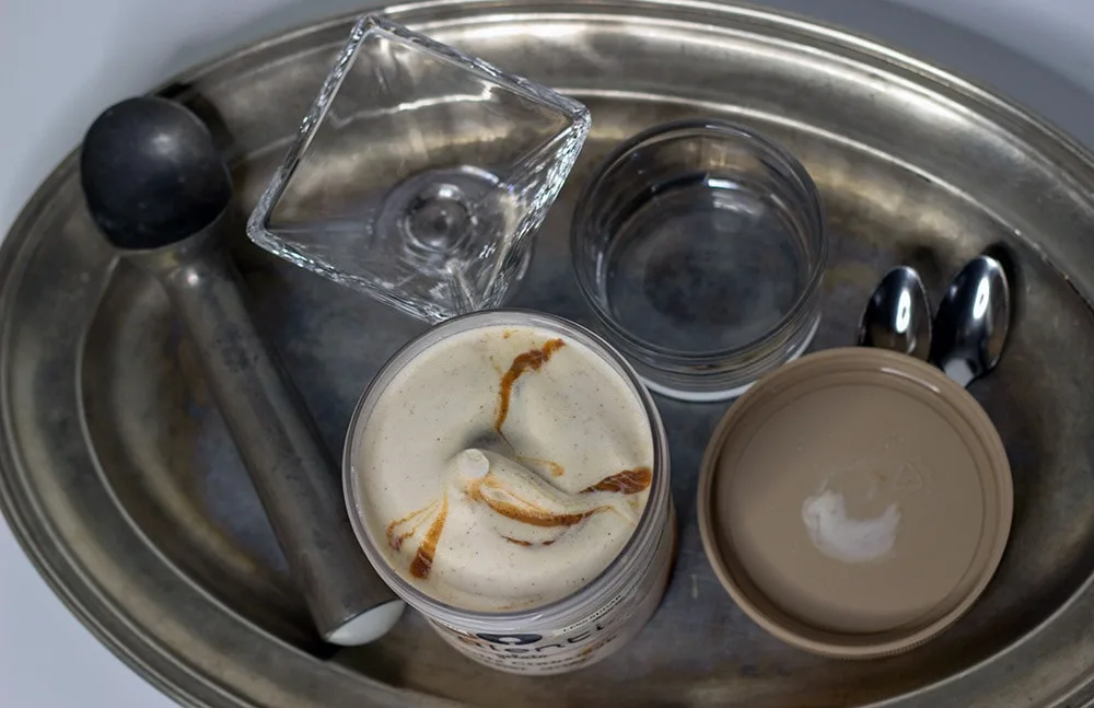 Talenti Gelato on a tray next to an ice cream scooper, dish, and spoons. 