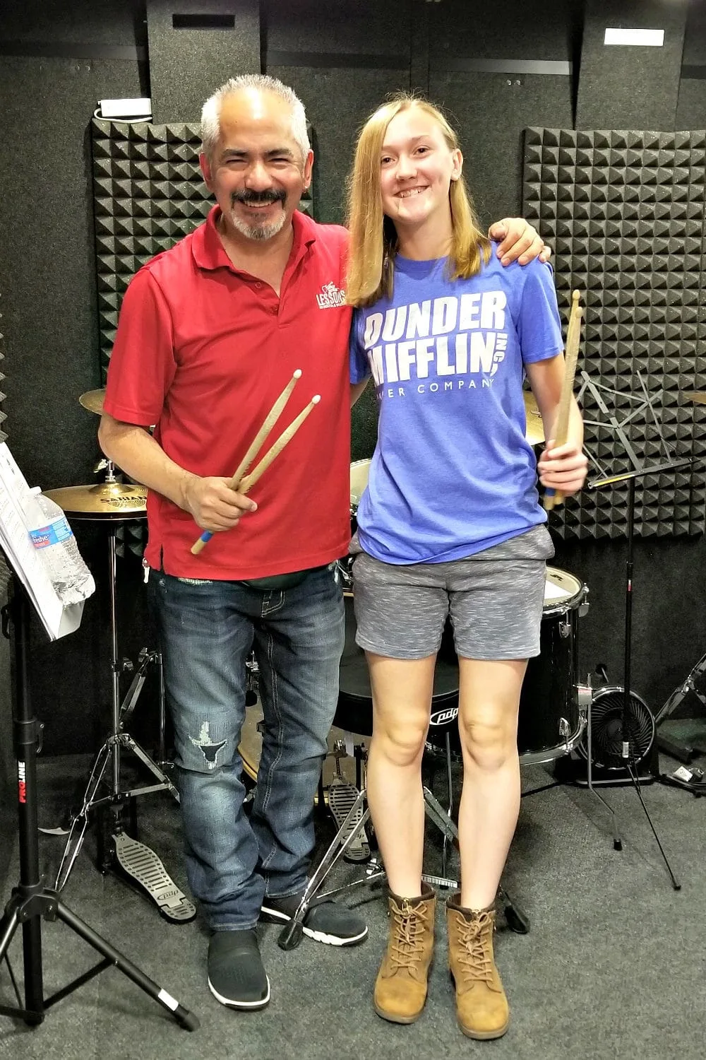 Chesney and Rudy from Guitar Center standing by the drum set. 