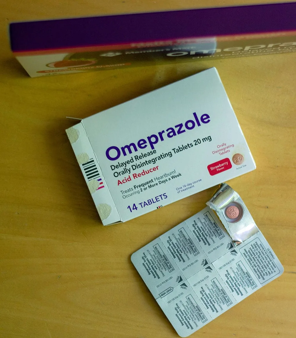 Box of heartburn medicine with a pill showing in the package sitting on a table. 