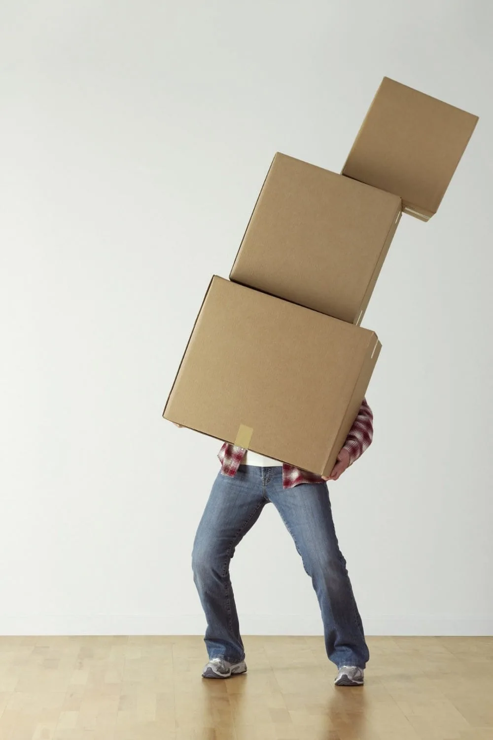 A person holding a huge stack of boxes that is about to fall. 