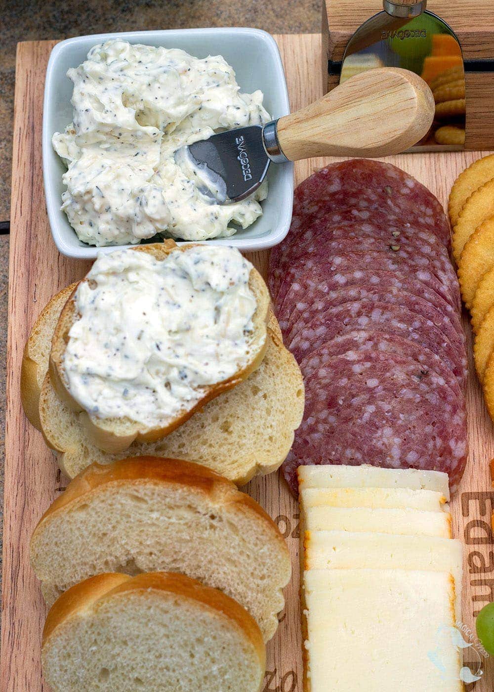 Cheesy garlic butter spread next to a board filled with cheese and meat. 