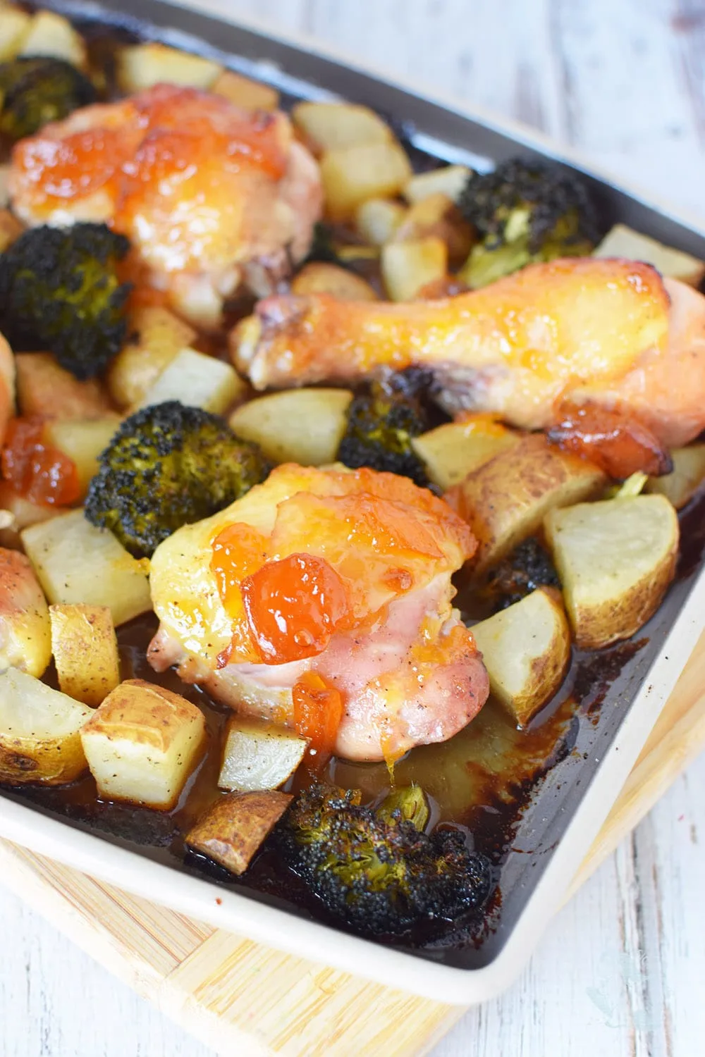 Chicken and veggies topped with peach preserves on a sheet pan. 
