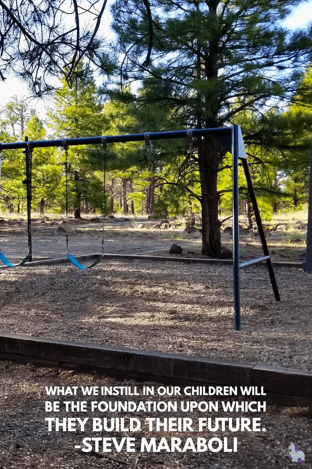 Swing sets in a park with trees. 