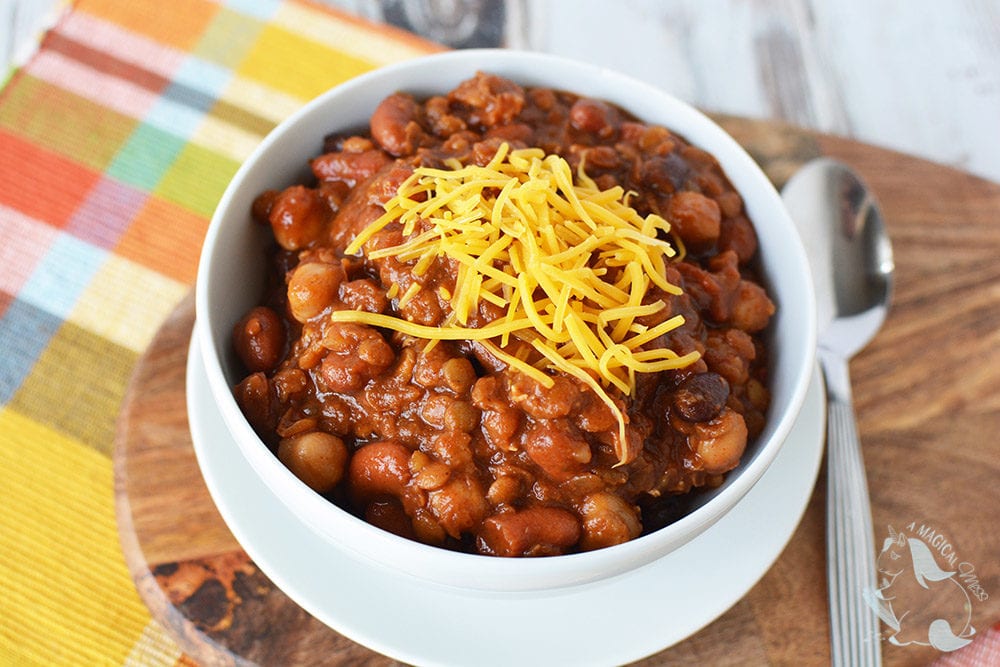 A bowl of bean chili topped with cheddar cheese.