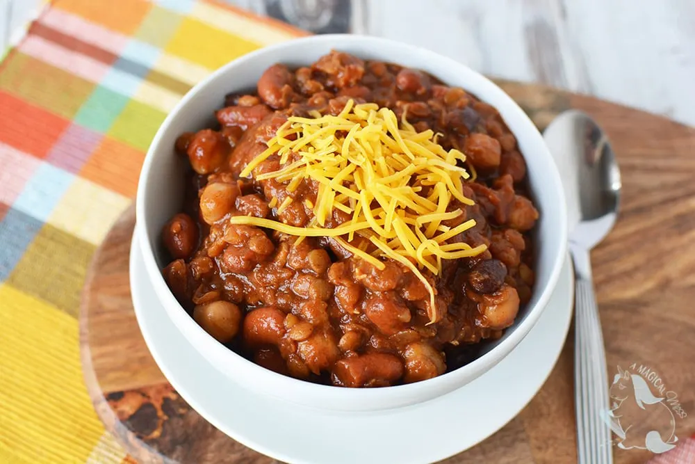 A bowl of bean chili topped with cheddar cheese. 