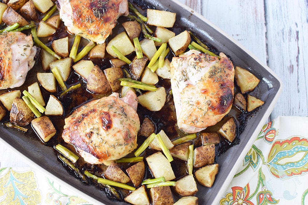 Chicken thighs baked on a sheet pan with potatoes and asparagus.