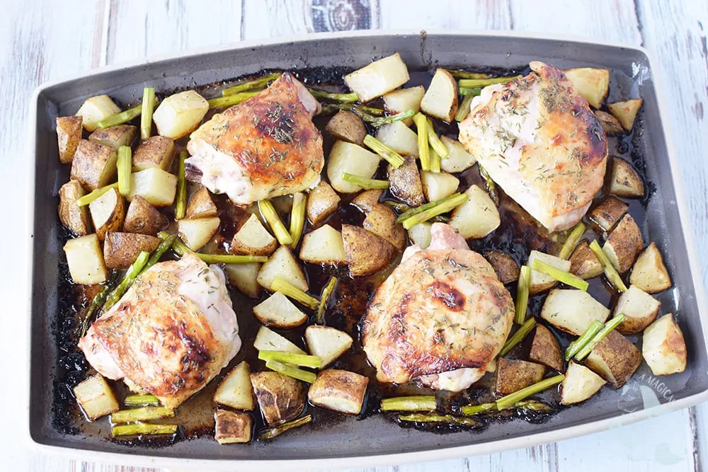 Chicken thighs with vegetables and potatoes on a sheet pan.