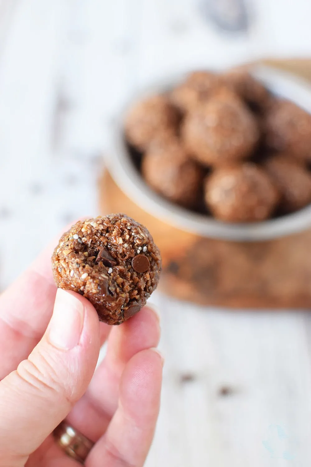 Holding a chocolate energy ball with a bite taken out of it. 