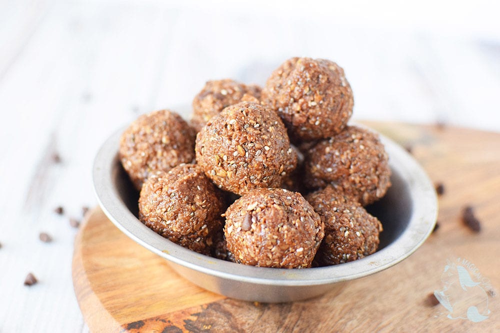 Chocolate energy balls with chocolate chips in a bowl on a board.