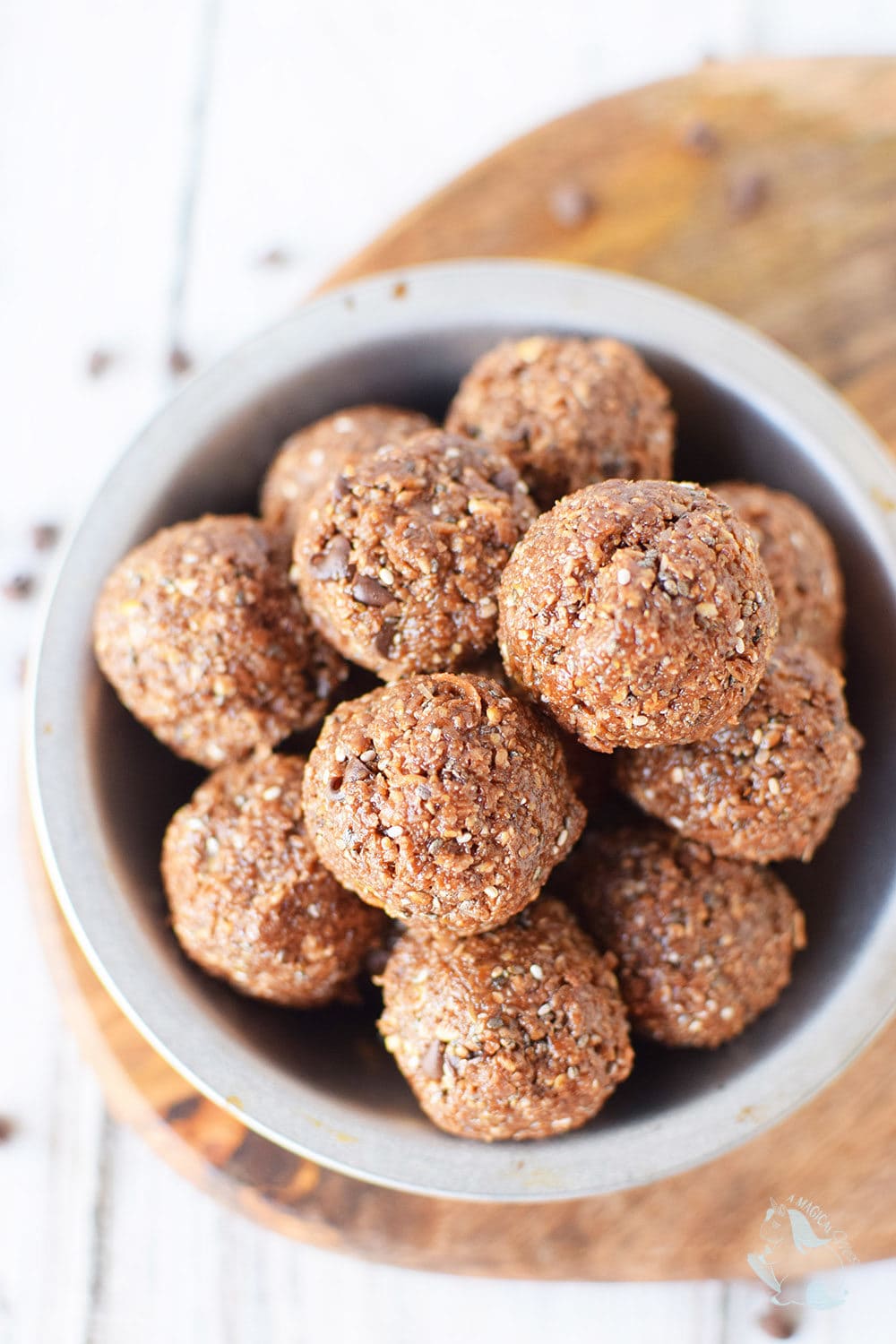 Chocolatey energy balls in a bowl with chips on the table.