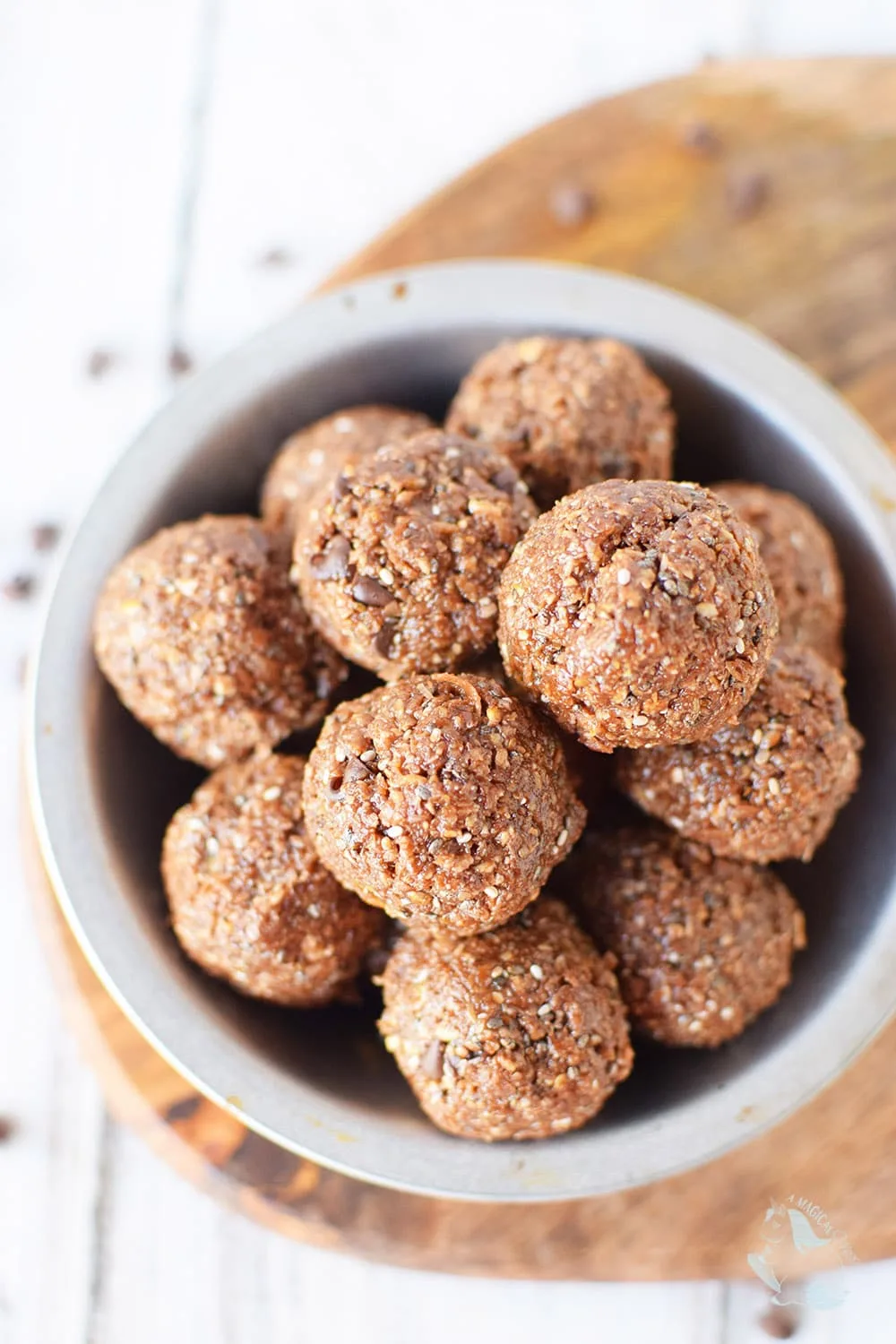 Chocolatey energy balls in a bowl with chips on the table. 