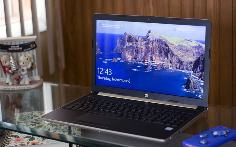 Laptop on a desk next to a phone and a figurine. 