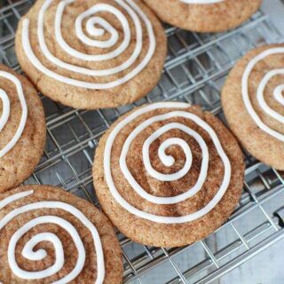 Cinnamon cookies on a baking rack with icing swirl