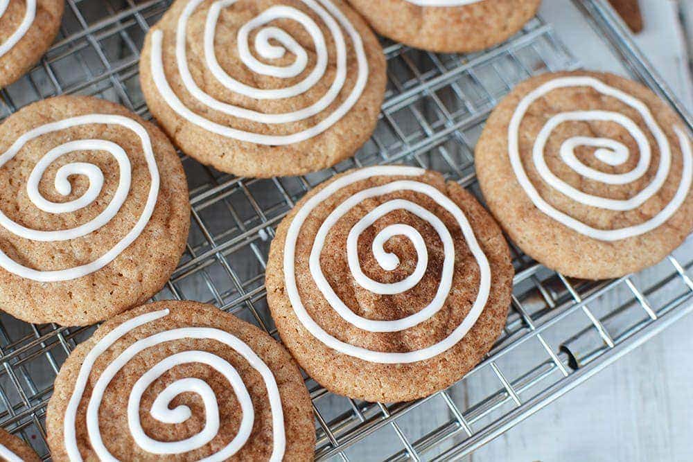 Cinnamon cookies on a baking rack with icing swirl 