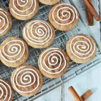 Cinnamon cookies with icing swirl on rack with cinnamon sticks
