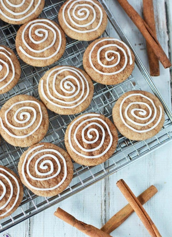 Cinnamon cookies with icing swirl on rack with cinnamon sticks