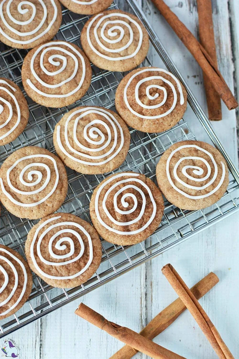 Cinnamon cookies with icing swirl on rack with cinnamon sticks