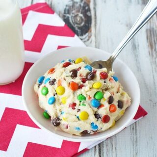 Cookie dough in a bowl with a spoon and a glass of milk.