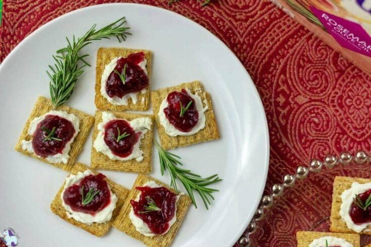 Cream cheese, cranberry jam, and fresh rosemary on a Triscuit
