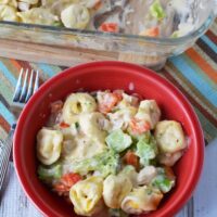 chicken tortellini with cream sauce and veggies in a red bowl