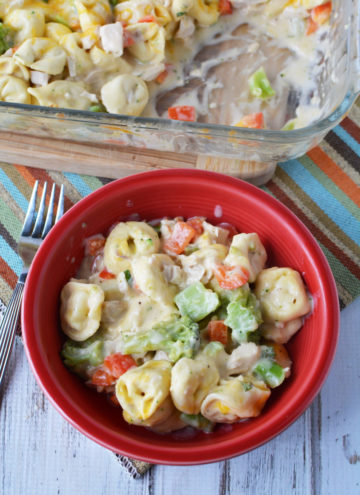 chicken tortellini with cream sauce and veggies in a red bowl