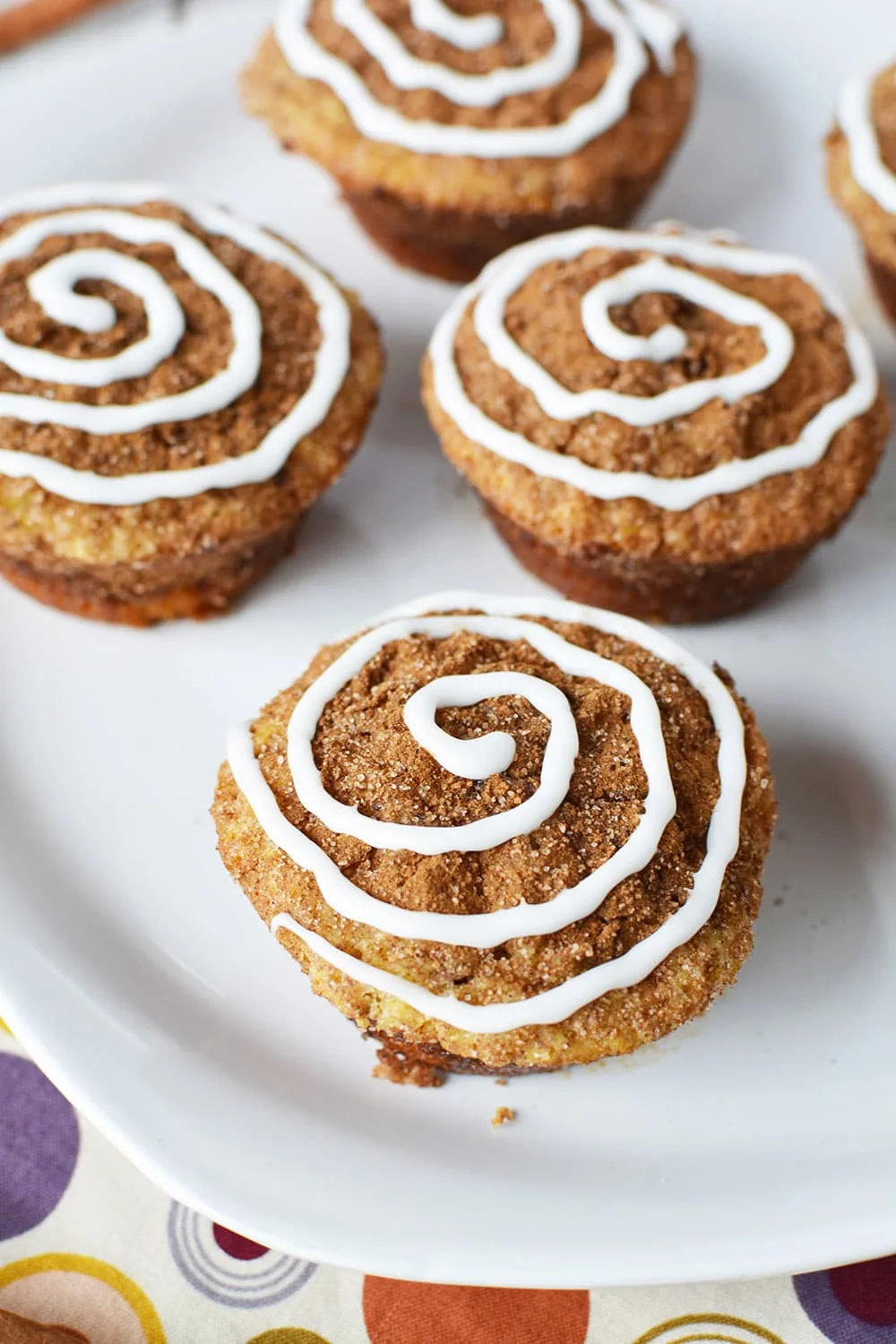 Cinnamon muffins on a plate. Cinnamon topping and icing swirl to give cinnamon roll appearance. 