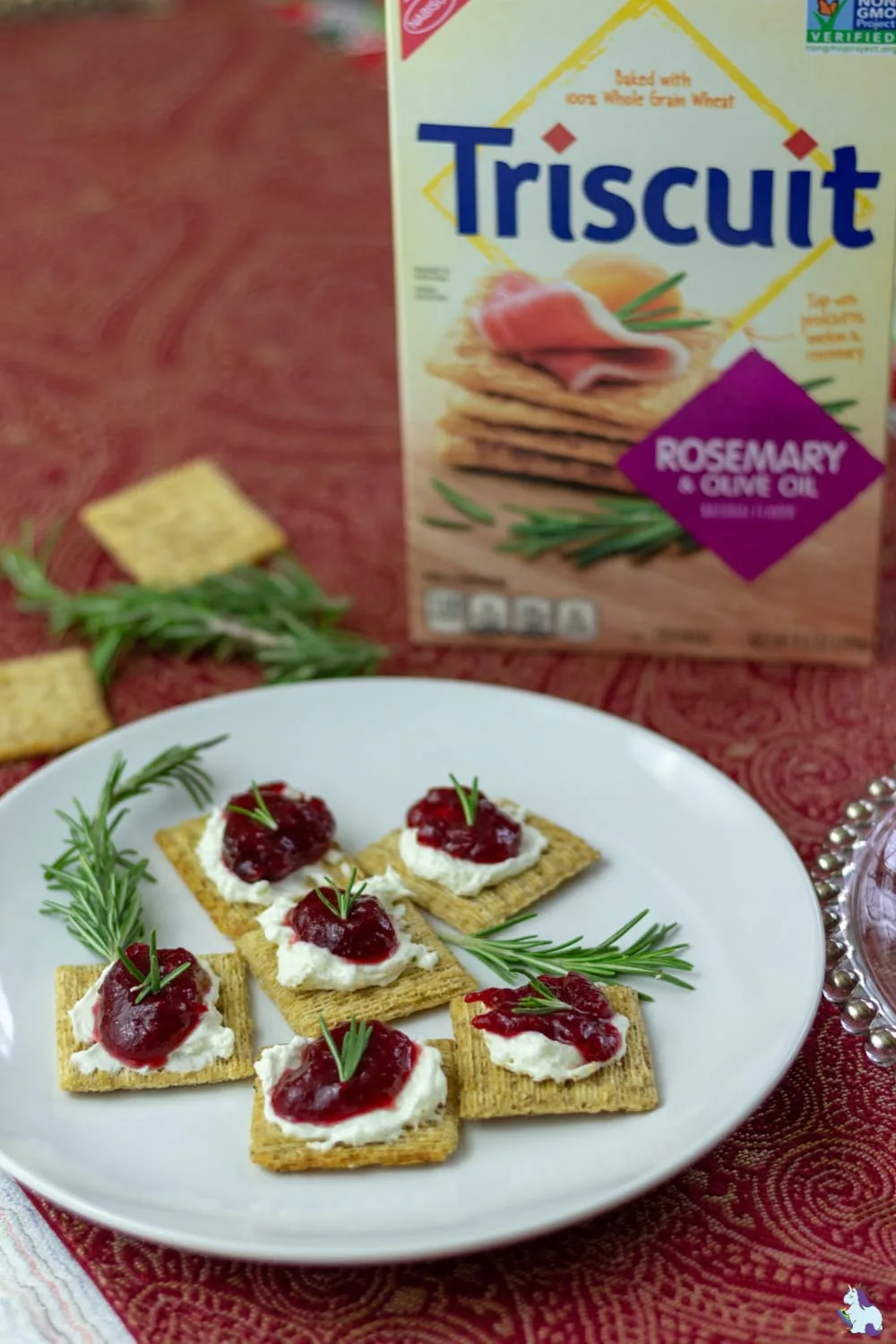 Triscuits with cranberry jam topping on a plate with a box of Triscuits