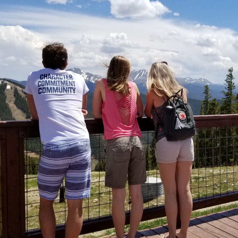 Two teens and their mom overlooking a ski resort in the summer.