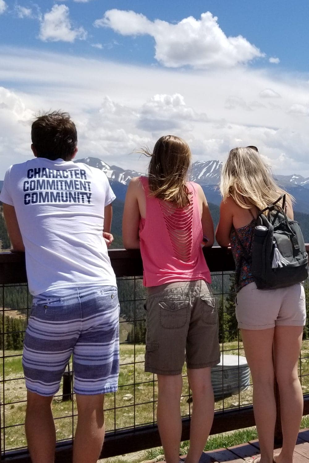 Mom and her two teens look out over a mountain view.