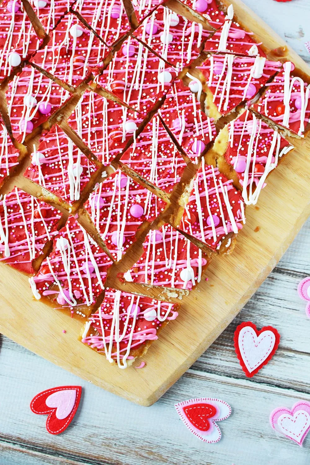 Cracker candy with red, white, and pink chocolates on a cutting board. 