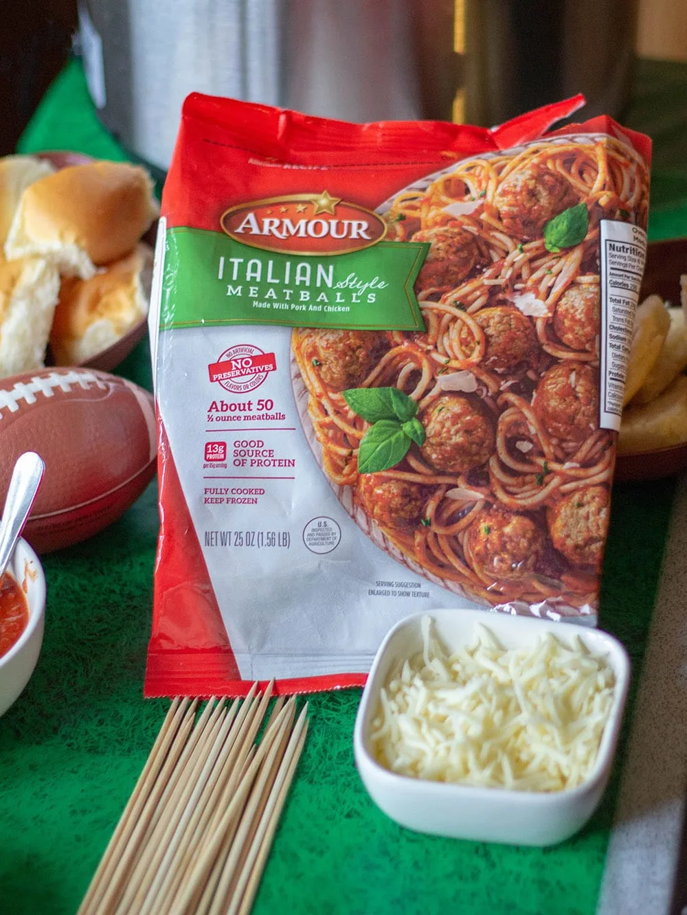 Bag of Armour Meatballs on a table with cheese and skewer sticks. 