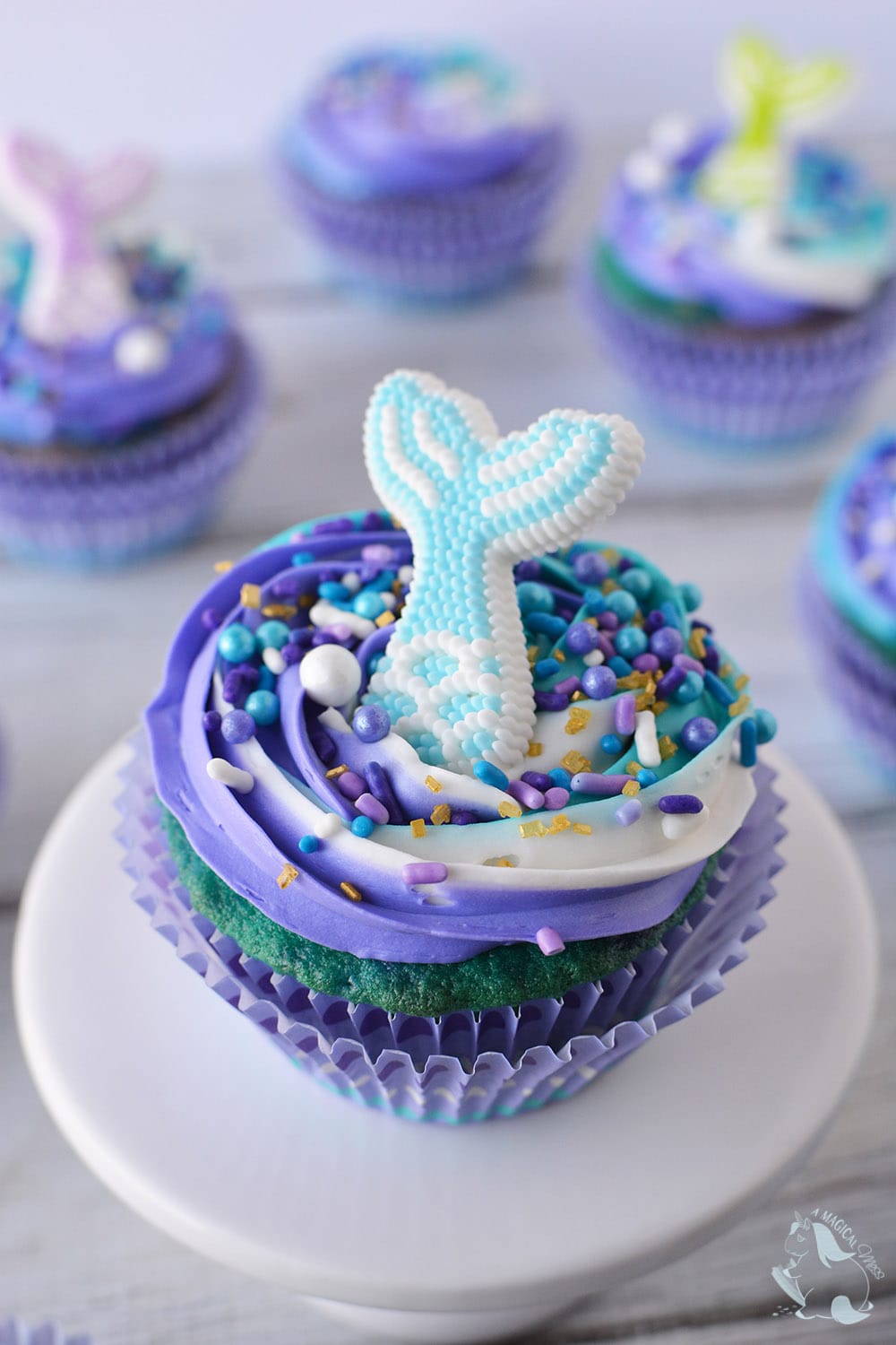 Blue, purple and teal cupcake on a white plate.