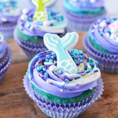 Mermaid cupcake sitting on a board with more cupcakes in the background.