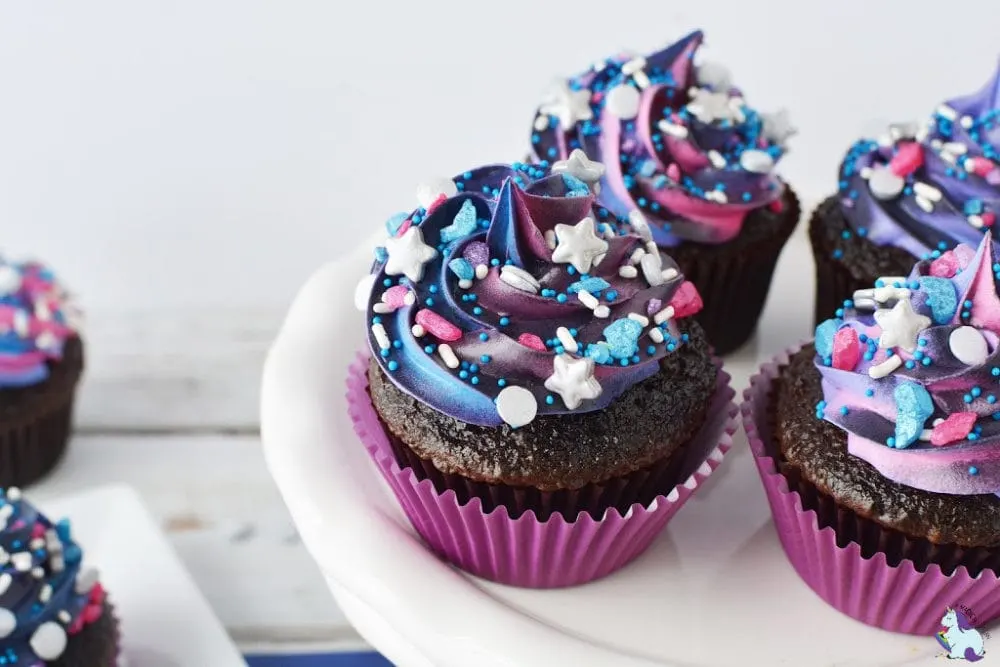Galaxy cupcakes on white plate.
