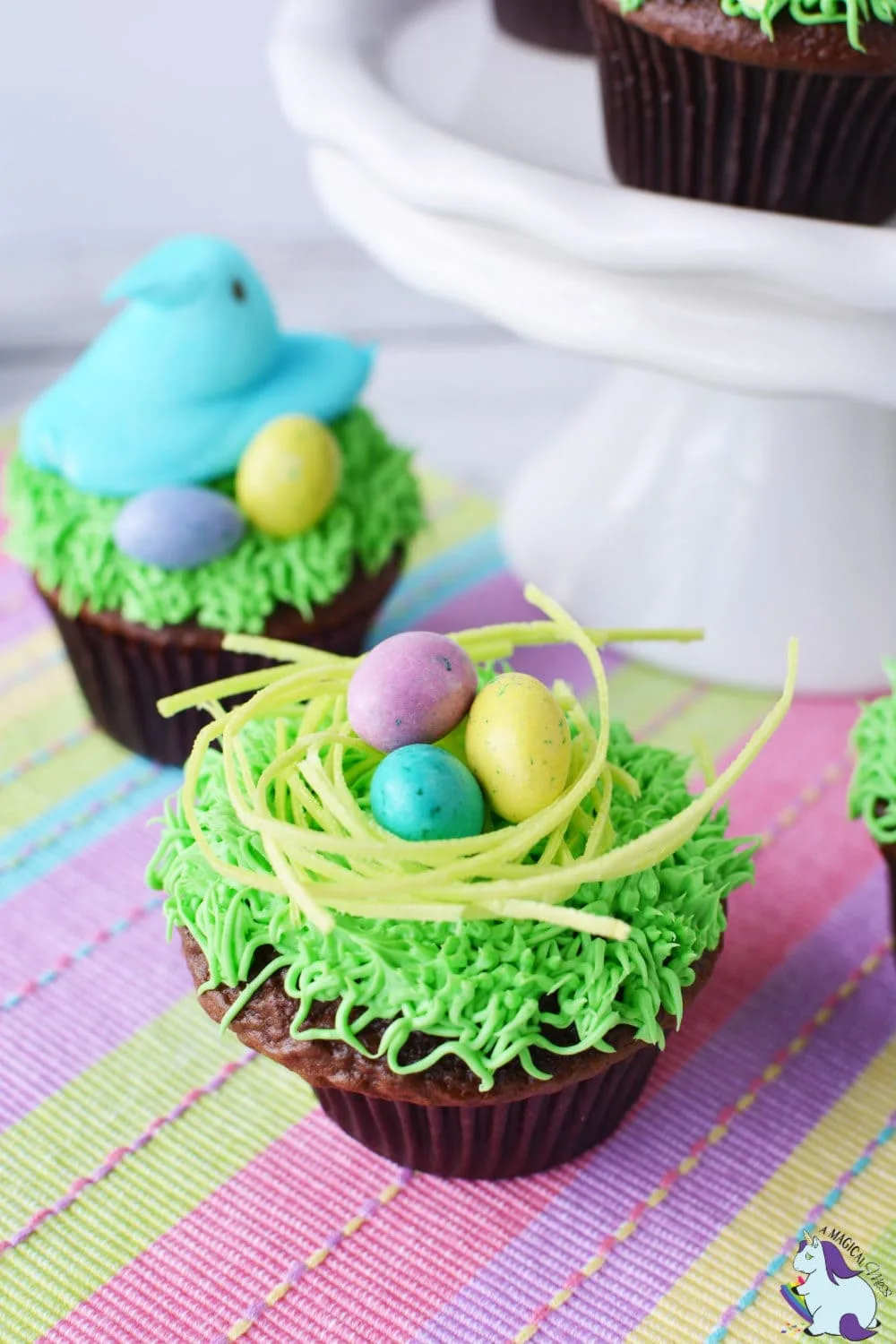 Chocolate cupcakes topped with Easter eggs, edible grass, and marshmallow Peeps. 