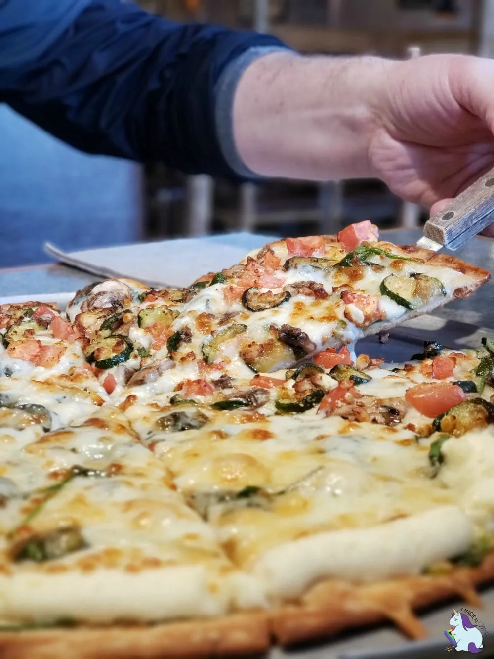 MacKenzie River Pizza in Bozeman holding a spatula to remove a slice of pizza. 