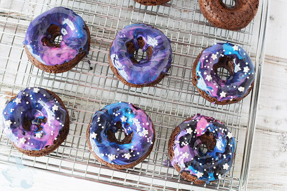 Galaxy cake donuts with glaze on a rack. 