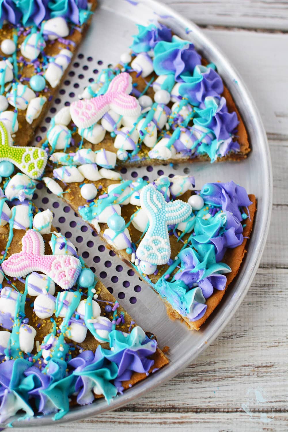 Mermaid cookie pizza sliced on baking pan.