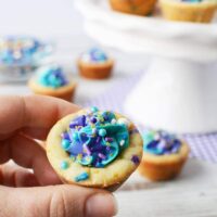 Holding a cookie cup filled with blue and purple frosting and sprinkles.