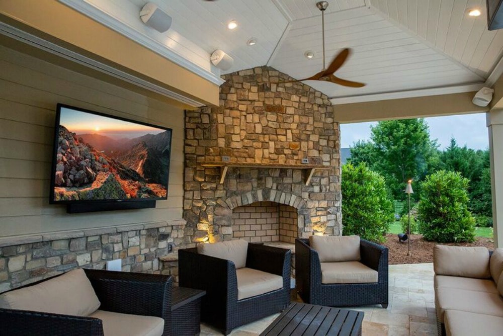 Gorgeous outdoor patio with a fireplace, couches, and a TV. 