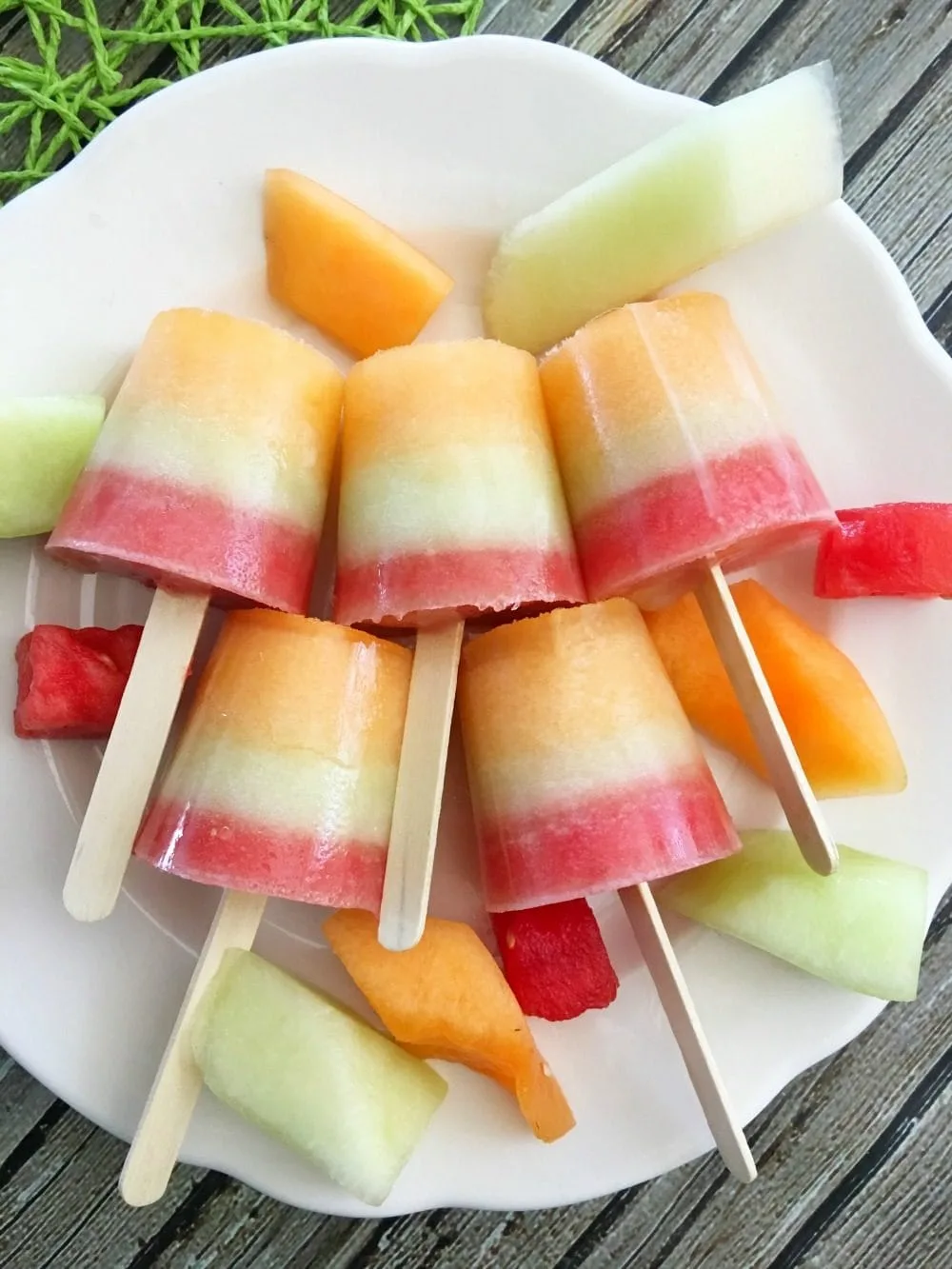 Layered melon popsicles on a plate.