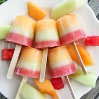 Layered melon popsicles on a plate.